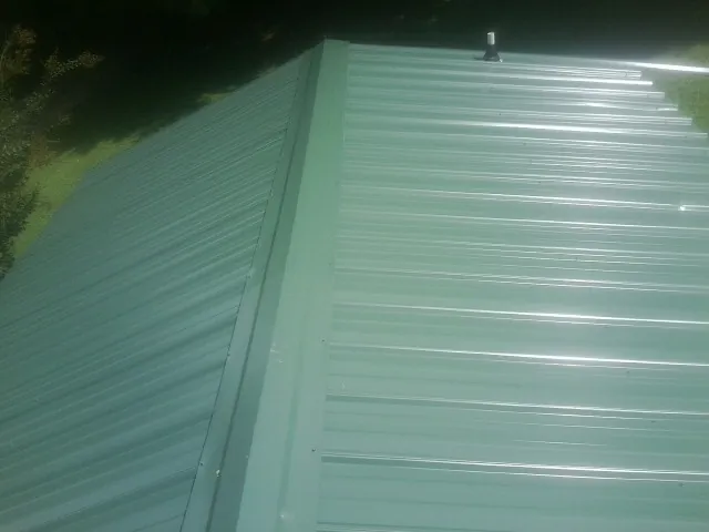 New green metal panels meeting at the ridge of a roof — Flat Roof Repair work by our crew in Mcallen