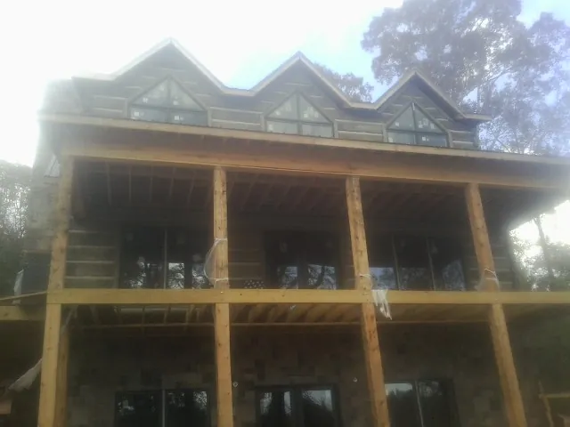 Dormers and porch framing on a large log home under construction — Roof Coating work by our crew in Mcallen