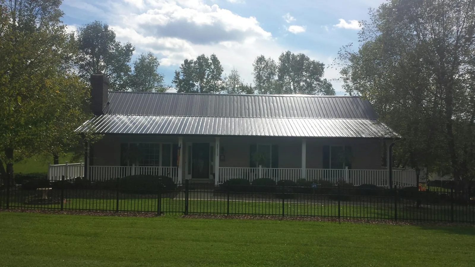 Gray metal roof on a brick ranch with a full width front porch — Gutter Guard Installation work by our crew in Mcallen